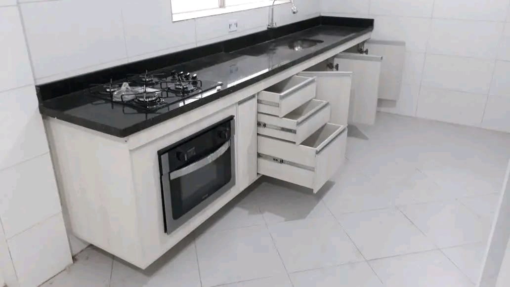 Cozinha planejada com bancada preta e eletrodomésticos embutidos